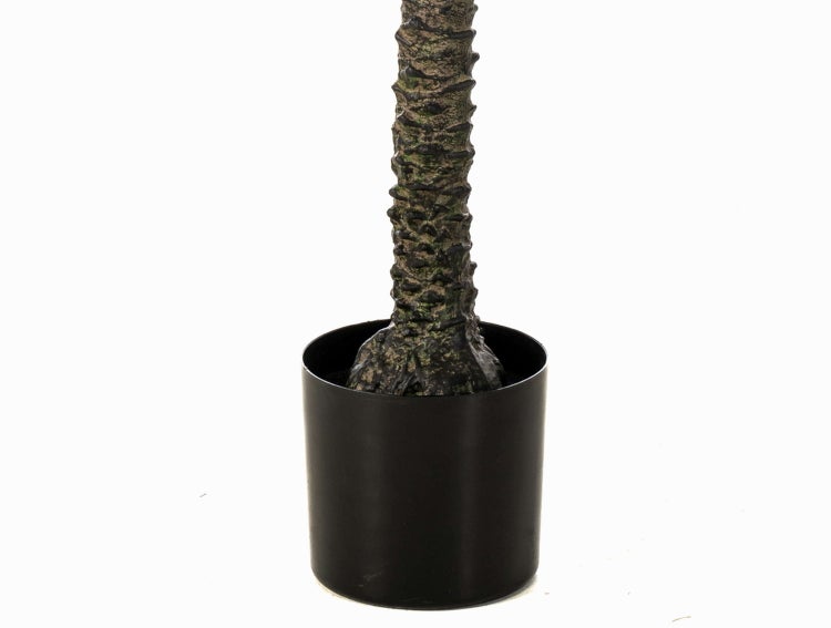 Detailaufnahme einer Kunstpflanze mit grünen Blättern in einem dunklen Topf.