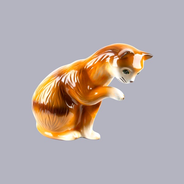 Dekorative Katzenfigur aus Keramik in sitzender Pose mit einer erhobenen Pfote.
