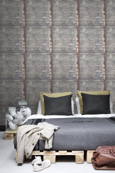 Schlafzimmer mit Wandtapete in Betonplattenoptik, Bett auf Europaletten und dekorativen Elementen