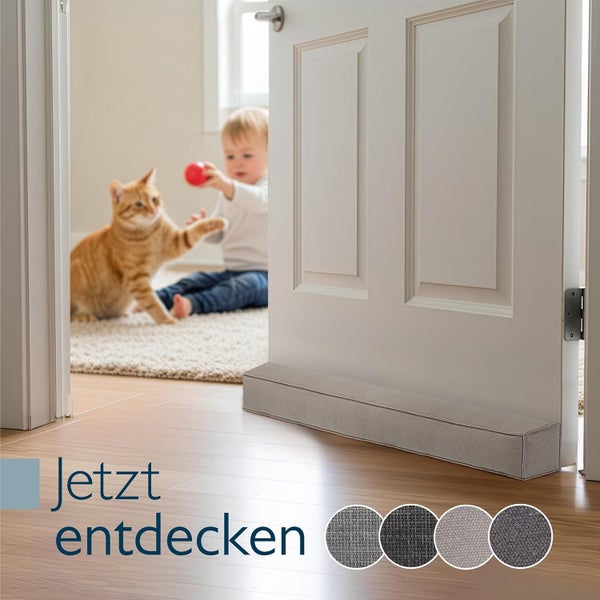 Ein rechteckiger Zugluftstopper aus Stoff liegt vor einer weißen Tür auf hellem Holzboden im Wohnzimmer mit spielendem Kind und Katze.