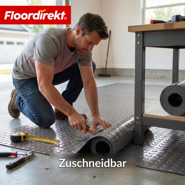 Ein Mann schneidet eine Bodenmatte mit Noppenmuster in einer Garage zu, Werkzeuge liegen bereit, FloorDirekt Logo