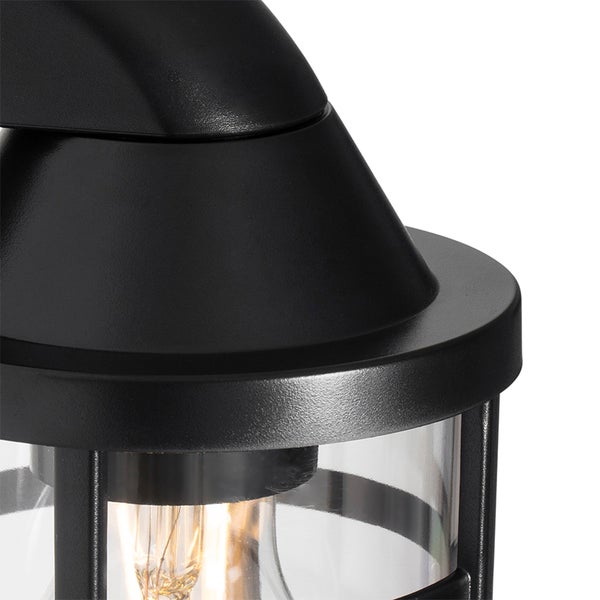 Schwarze Außenwandleuchte aus Metall mit Glaseinsatz und sichtbarem Leuchtmittel.