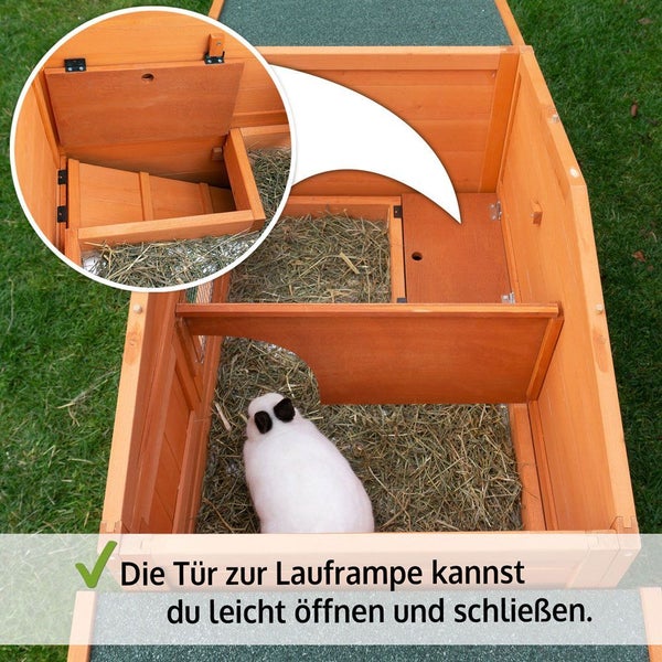 Innenansicht eines Kleintierstalls aus Holz mit Heu und Kaninchen, Detail der verschließbaren Luke zur Lauframpe.