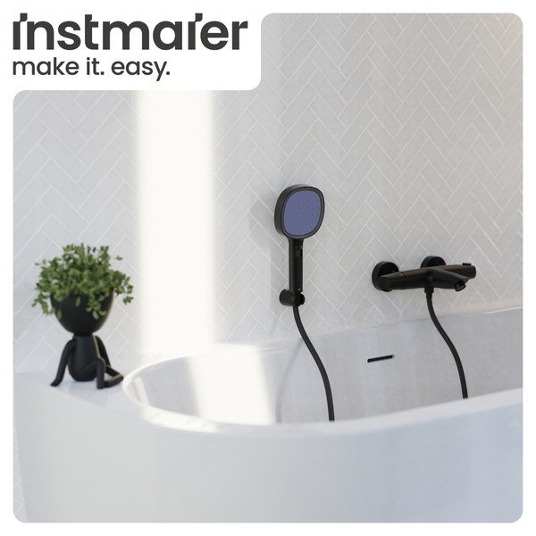 Helles Badezimmer mit weißer Badewanne, schwarzer Armatur und Handbrause an weißer Fliesenwand mit Fischgrätmuster. Instmaier Logo.