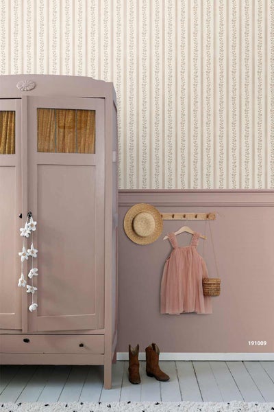 Vliestapete mit floralen Streifen über einer Wandvertäfelung in einem hellen Kinderzimmer neben einem Kleiderschrank aus Holz.