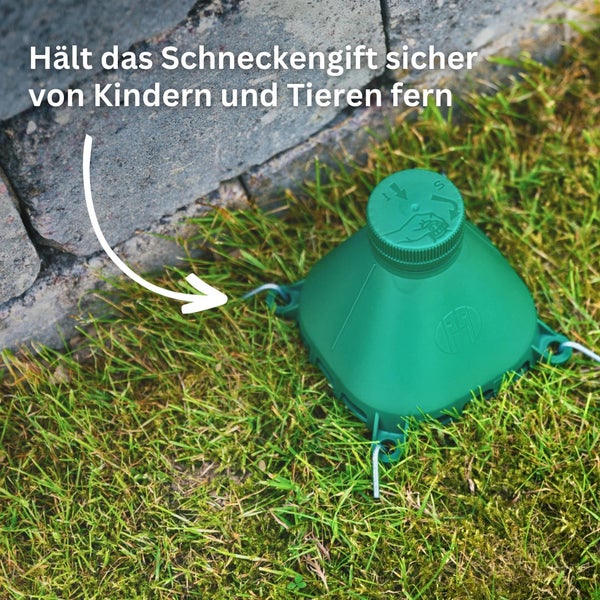 Schneckenkornfalle für den Garten zum Schutz vor Kindern und Haustieren mit Deckel und Erdankern im Gras aufgestellt.