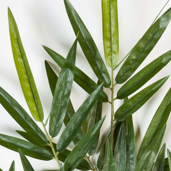 Grüner künstlicher Bambuszweig mit langen, spitzen Blättern aus Kunststoff.