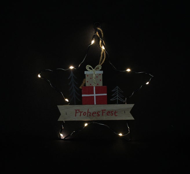 Beleuchteter Stern aus Metall mit Holzmotiv Geschenken und Tannenbäumen sowie Aufschrift Frohes Fest als Weihnachtsdekoration zum Aufhängen