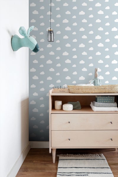 Kinderzimmer mit Wolkentapete, Wickelkommode, Stofftierkopf und Hängelampe.