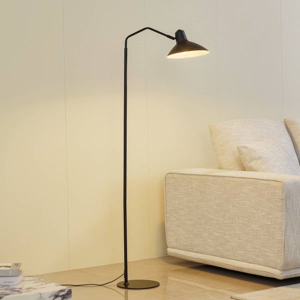 Schwarze Stehlampe mit konischem Lampenschirm neben einem Sofa