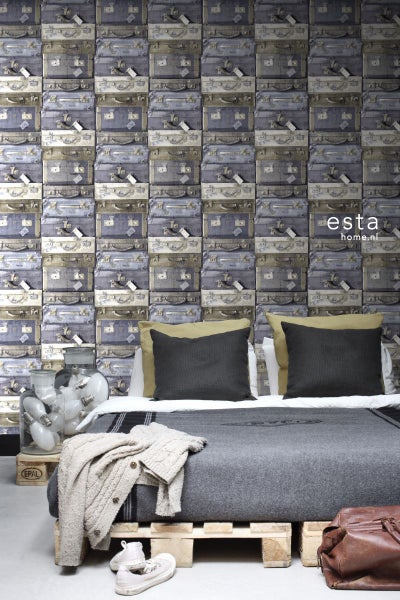 Schlafzimmer mit einer Wandtapete mit gestapelten Koffern, einem Bett auf einer Palette und einer Glühbirnenkollektion in einem Glas