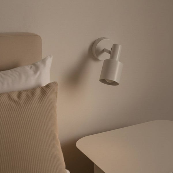 Wandleuchte neben Nachttisch und Bett