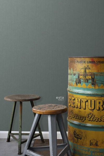 Szene mit grauer Textiltapete, zwei Hockern und einer verzierten Metalletonne