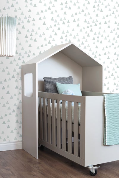 Kinderbett mit Hausrahmen, Kissen und Decke in einem hellen, kinderfreundlichen Raum.