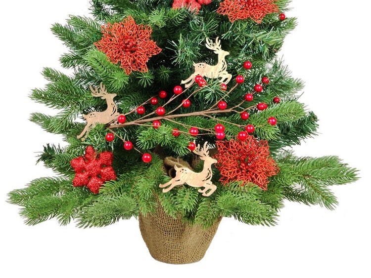 Künstlicher Weihnachtsbaum im Jutesack dekoriert mit Holzrentieren, Beeren und Blumen.
