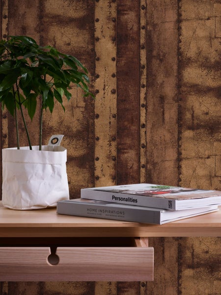 Dekoratives Interieur mit gemusterter Tapete, Zimmerpflanze und Büchern auf einem Tisch