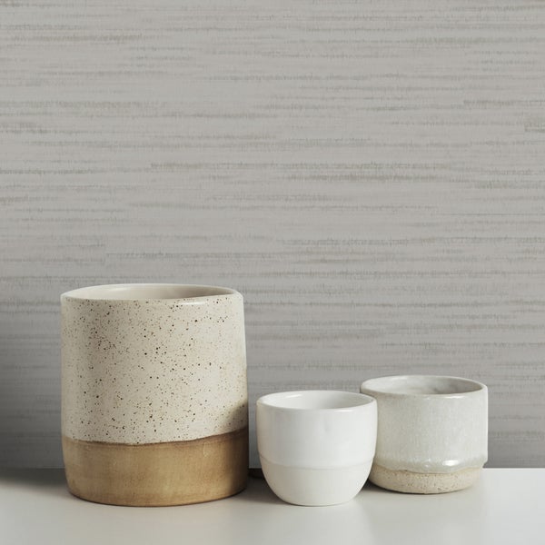 Dekorative Keramikgefäße auf einer weißen Oberfläche vor einer Wand mit Textiltapete