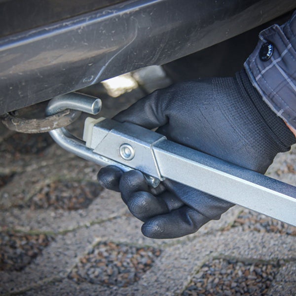 Eine Person mit Handschuhen befestigt eine Anhängerkupplung an einem Fahrzeug.