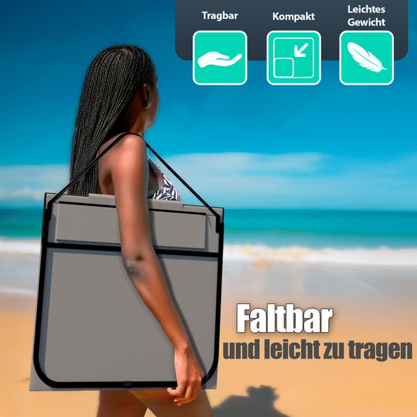 Frau trägt einen faltbaren, grauen Bollerwagen am Strand.