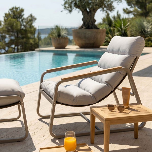 Moderner Garten-Loungesessel mit gepolsterter Auflage und Armlehnen aus Holz am Pool mit Beistelltisch und Hocker.