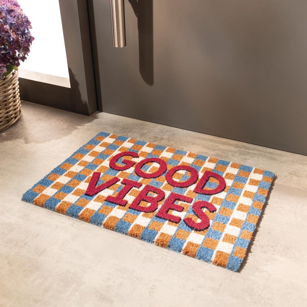 Fußmatte mit kariertem Muster und Good Vibes Schriftzug vor einer Haustür