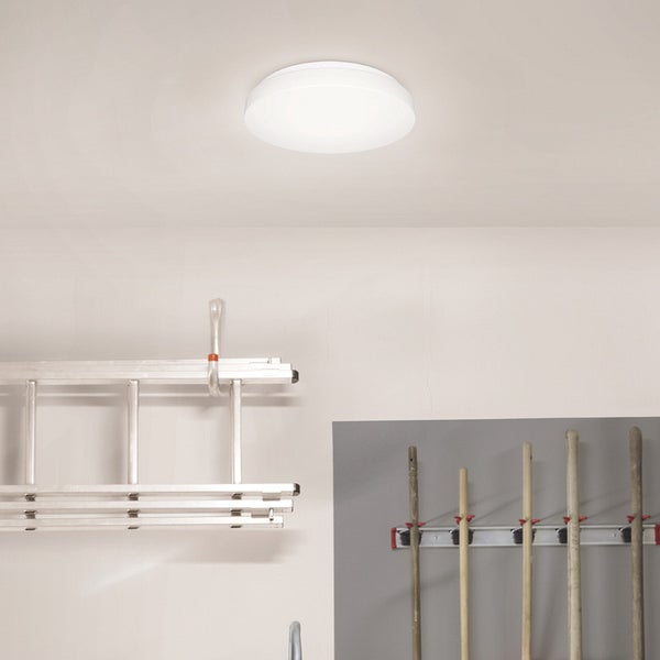 Einrichtungsszene mit braunem Sessel, Sideboard aus Holz und grünen Vorhängen vor einem Fenster