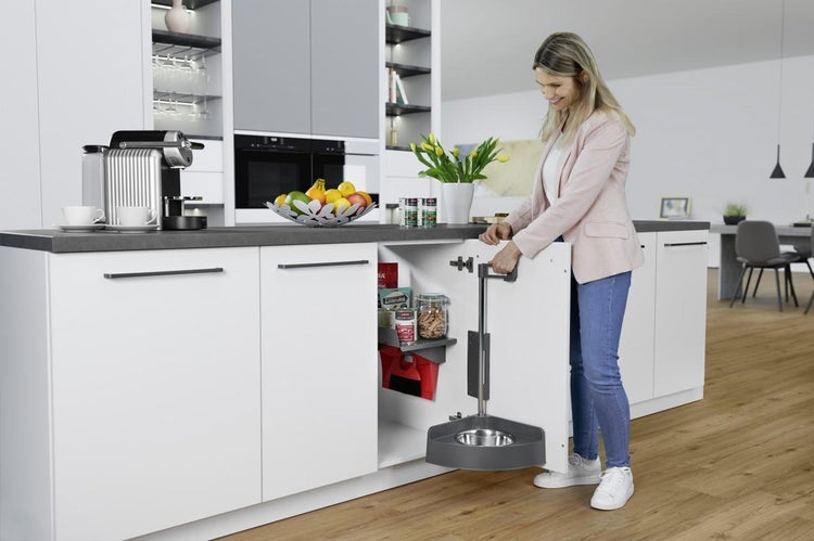 Frau öffnet einen weißen Küchenunterschrank in einer hellen Küche mit Auszugssystem für Tierfutter und integriertem Futternapf.