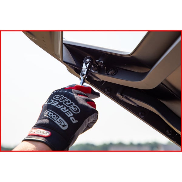 Eine Person befestigt mit einem Schraubenschlüssel eine Edelstahl-Pedalabdeckung im Auto. Ein roter Werkzeugkasten mit verschiedenen Schraubenschlüsseleinsätzen liegt daneben.