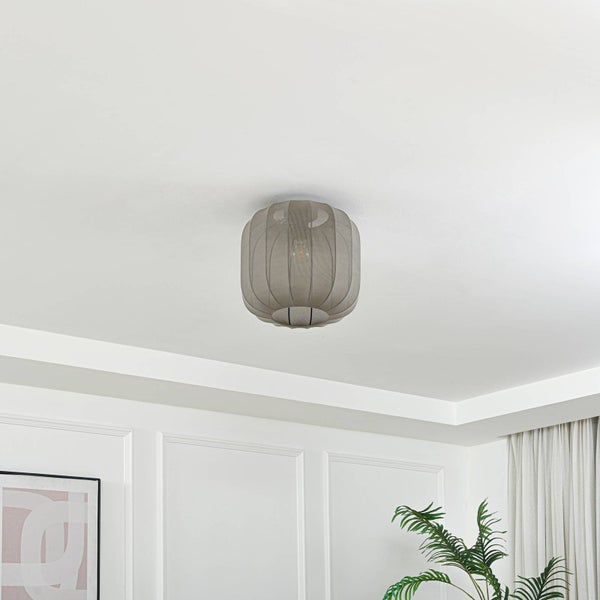 Ovale Deckenleuchte aus grauem Mesh-Gewebe an einer weißen Decke in einem hellen, modern gestalteten Raum mit Wandleisten.