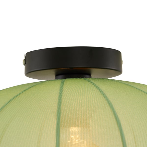 Nahaufnahme einer Deckenleuchte mit schwarzer Metallhalterung und grünem Textilschirm mit Rippenstruktur.