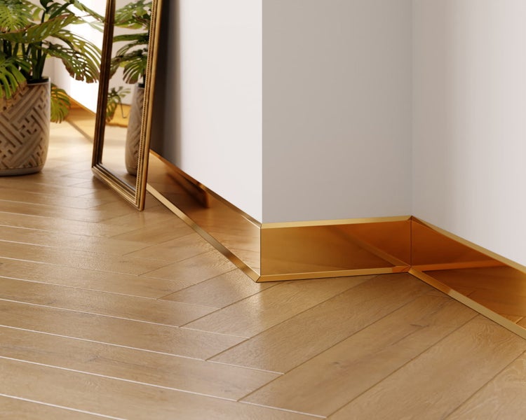 Raumecke mit goldfarbener Sockelleiste und Fischgrätparkett