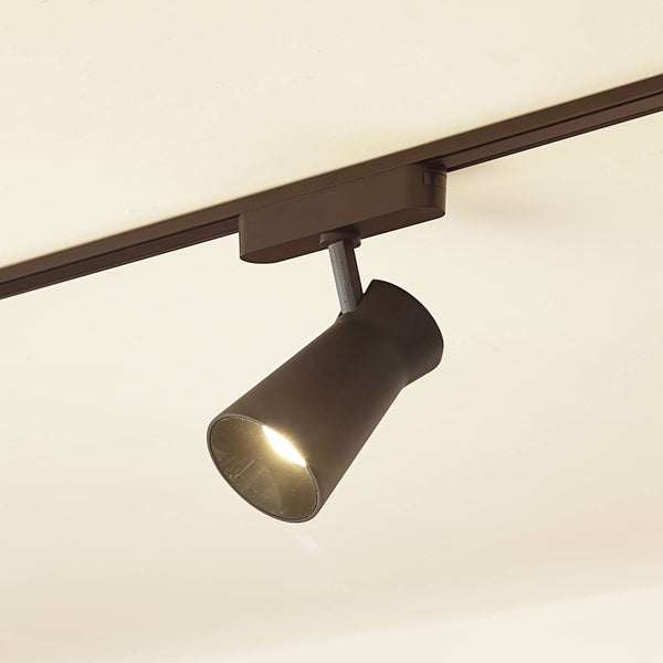 Verstellbarer Strahler für ein Schienensystem aus Metall in Dunkelbraun mit eingeschaltetem Leuchtmittel.