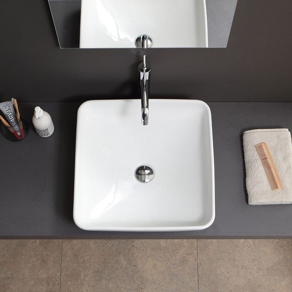 Draufsicht auf ein quadratisches weißes Keramik-Aufsatzwaschbecken mit Chrom-Armatur auf einer dunklen Waschtischplatte in einem modernen Badezimmer.