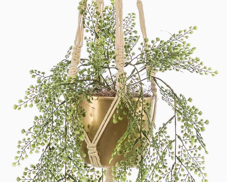 Künstlicher Farn in einem goldfarbenen Topf mit einer Makramee-Aufhängung
