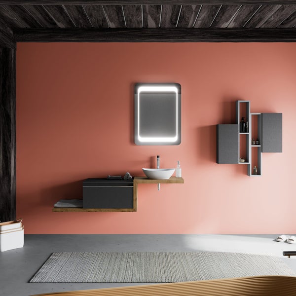 Modernes Badezimmer mit Waschtisch aus Holz, Aufsatzbecken, LED-Spiegel und Wandregalen vor terracottafarbener Wand.