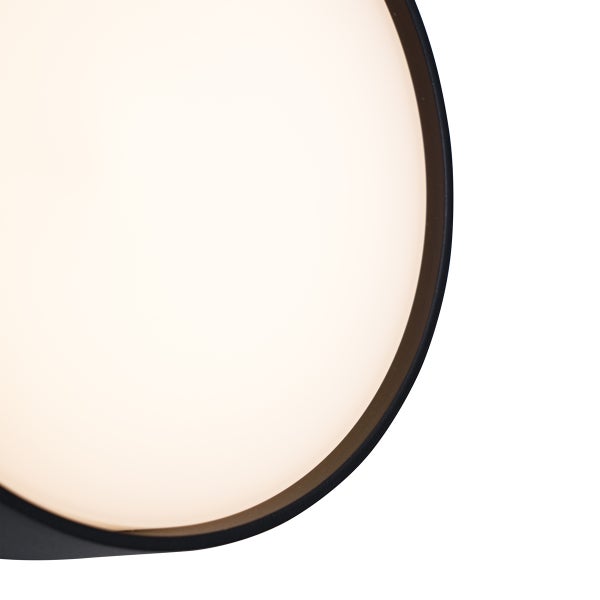 Nahaufnahme einer runden LED Leuchte mit schwarzem Metallrahmen und beleuchteter Oberfläche.