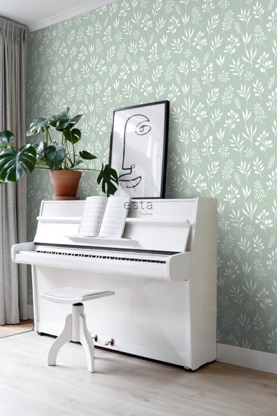 Zimmer mit floraler Tapete, weißem Klavier, Hocker und Zimmerpflanze