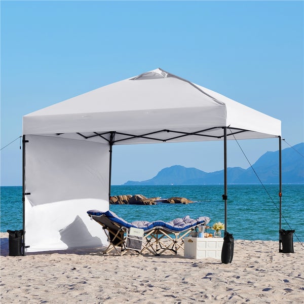 Szene mit einem weißen Strandpavillon, einem Liegestuhl und Zubehör am Strand.