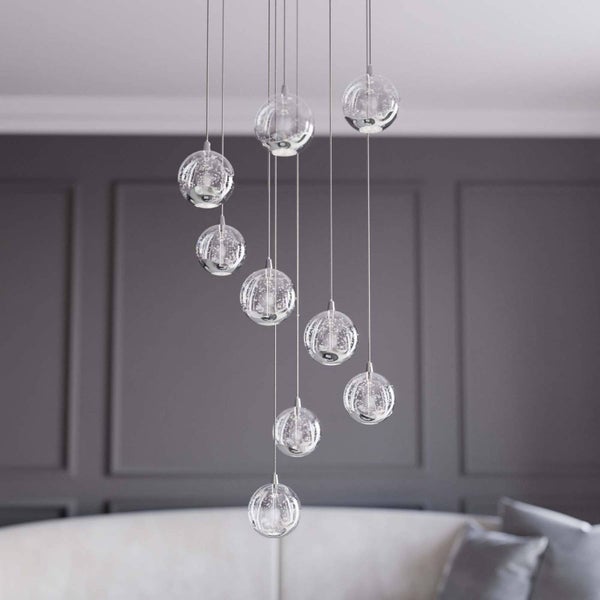 Moderne Pendelleuchte mit neun Glaskugeln in unterschiedlichen Höhen in einem Wohnzimmer.