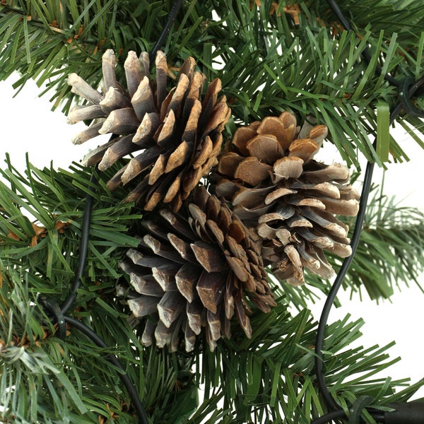 Detailaufnahme eines Weihnachtsbaumkranzes mit Tannenzweigen und drei Tannenzapfen