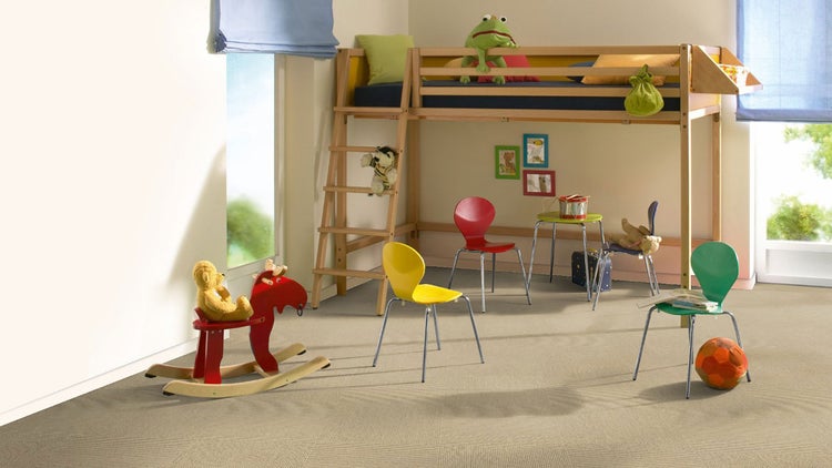 Hell eingerichtetes Kinderzimmer mit strukturiertem Teppichboden, Hochbett aus Holz, Stühlen aus Kunststoff und Metall sowie einem Schaukelpferd.
