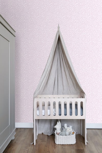 Helles Kinderzimmer mit gemusterter Tapete, Babybett und Kleiderschrank