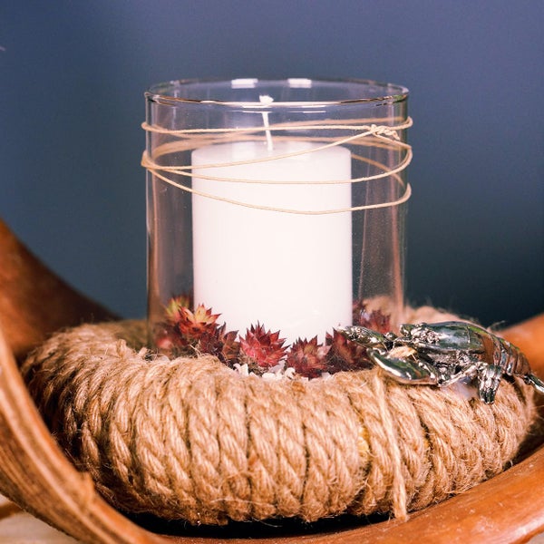Dekorative Kerze in Glashülle auf Jutebasis mit Metallkrebs