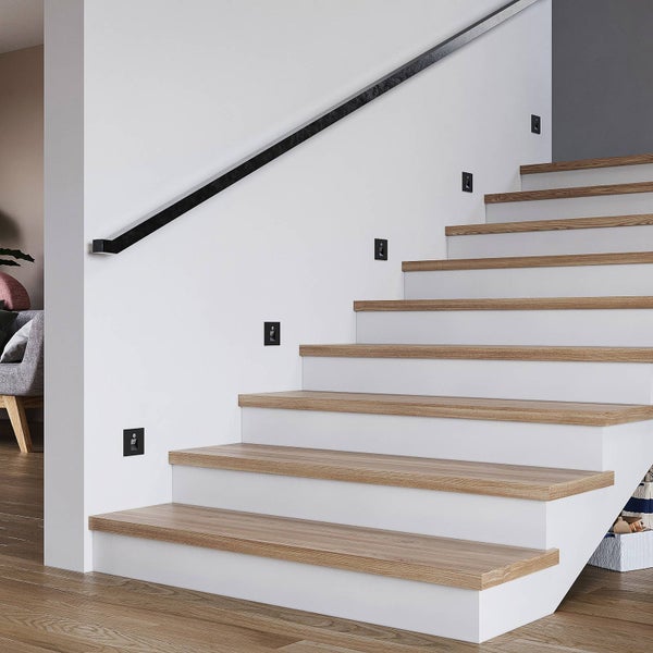 Moderne Treppe mit Holzstufen und weißen Setzstufen. Schwarze quadratische Wandeinbauleuchten dienen als Treppenbeleuchtung.