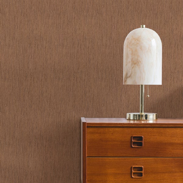 Braune Tapete mit vertikaler Leinenstruktur an einer Wand hinter einer Holzkommode und einer Marmorlampe.