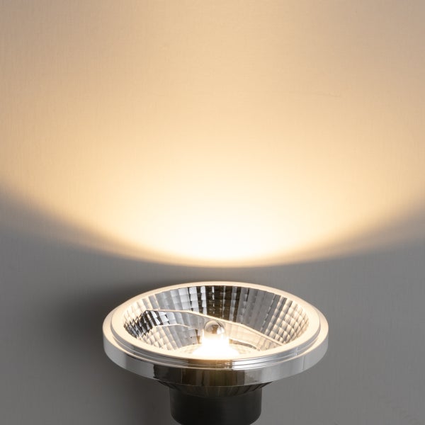 AR111 LED Leuchtmittel eingeschaltet mit warmweißem Lichtkegel an einer Wand.