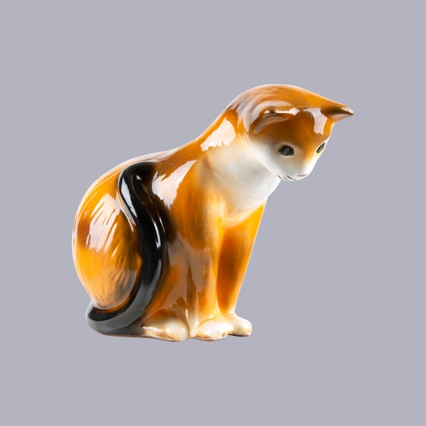 Dekofigur Katze aus Keramik, sitzend, glänzend lasiert, braun-weiß gemustert.