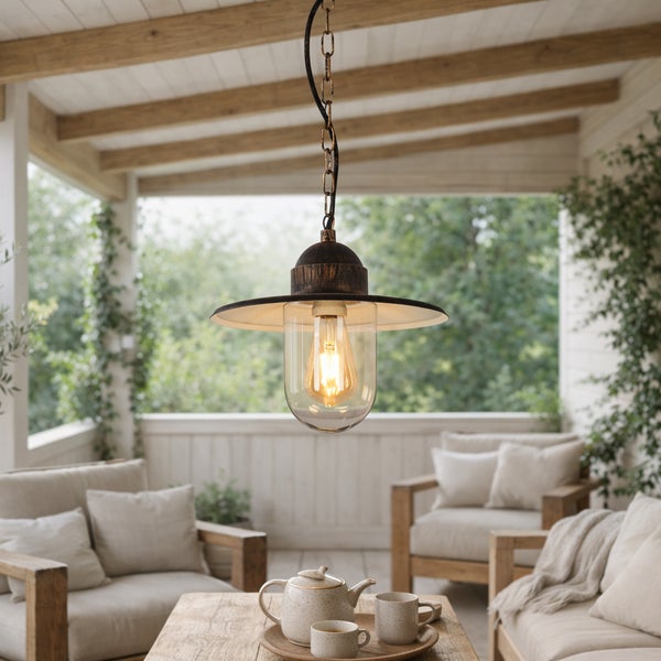 Rustikale Außenpendelleuchte mit Glasschirm auf einer hellen Holzterrasse mit gemütlichen Loungemöbeln und Teegeschirr.