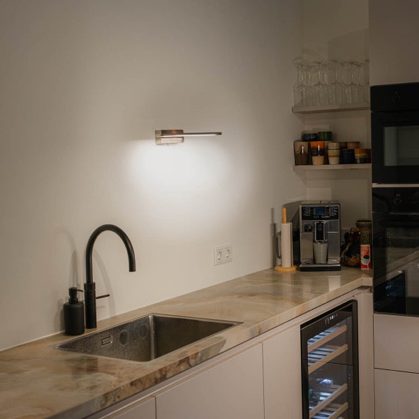 Küchenszene mit Spüle, Armatur, Wandleuchte und Küchengeräten auf einer Arbeitsplatte