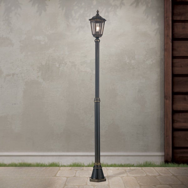 Klassische Kandelaber-Außenleuchte mit hohem Mast für den Garten auf einem Steinboden vor einer Wand.